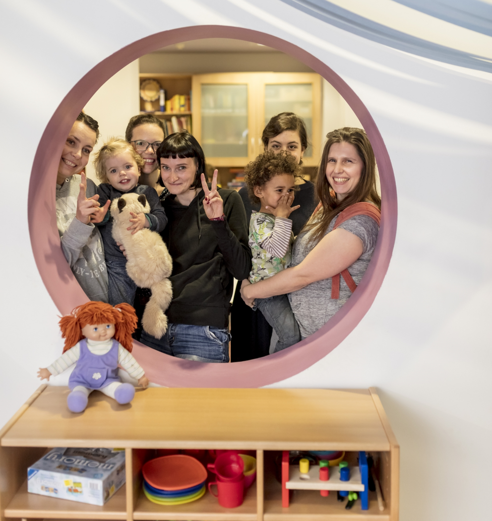 Group photo of several families with young children on the family floor of the family center – a place for connection, community, and early childhood support.