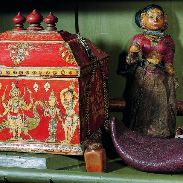 Detail from the India cabinet in the Baroque Cabinet of Artefacts and Natural Curiosities featuring an ornate idol casket, an ethnographic doll, and a traditional Indian shoe.
