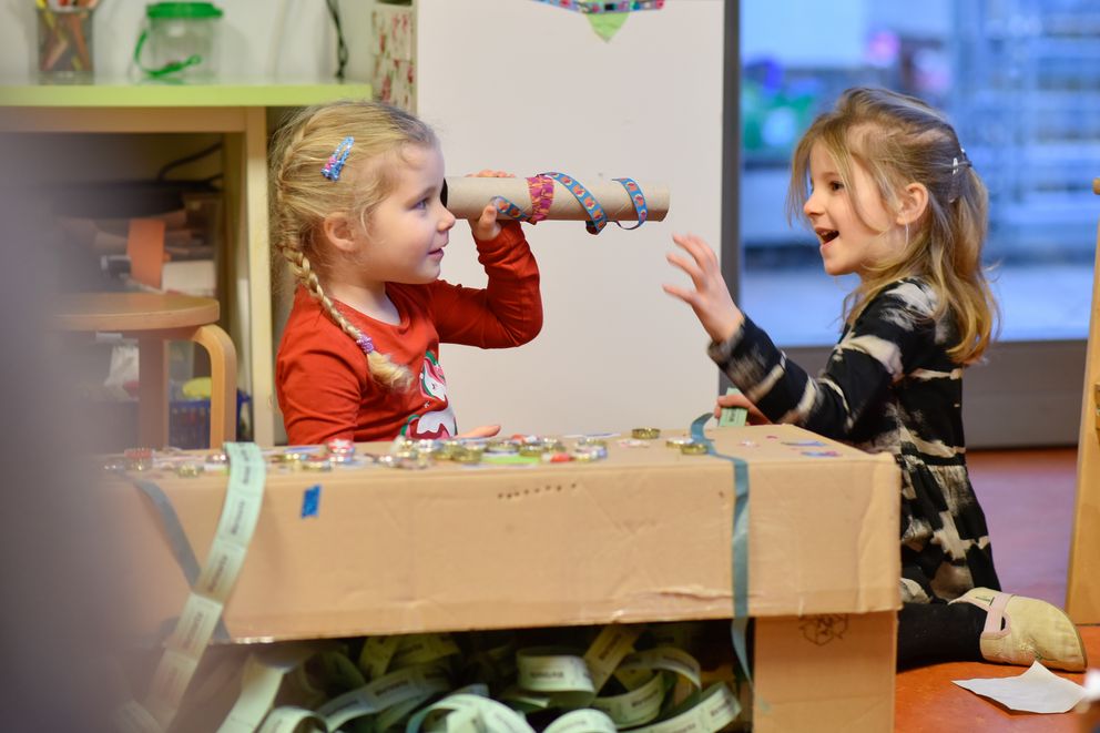 Zwei Kinder spielen mit einem langen Rohr aus Pappkarton – kreative Nutzung von Alltagsmaterialien im Hort