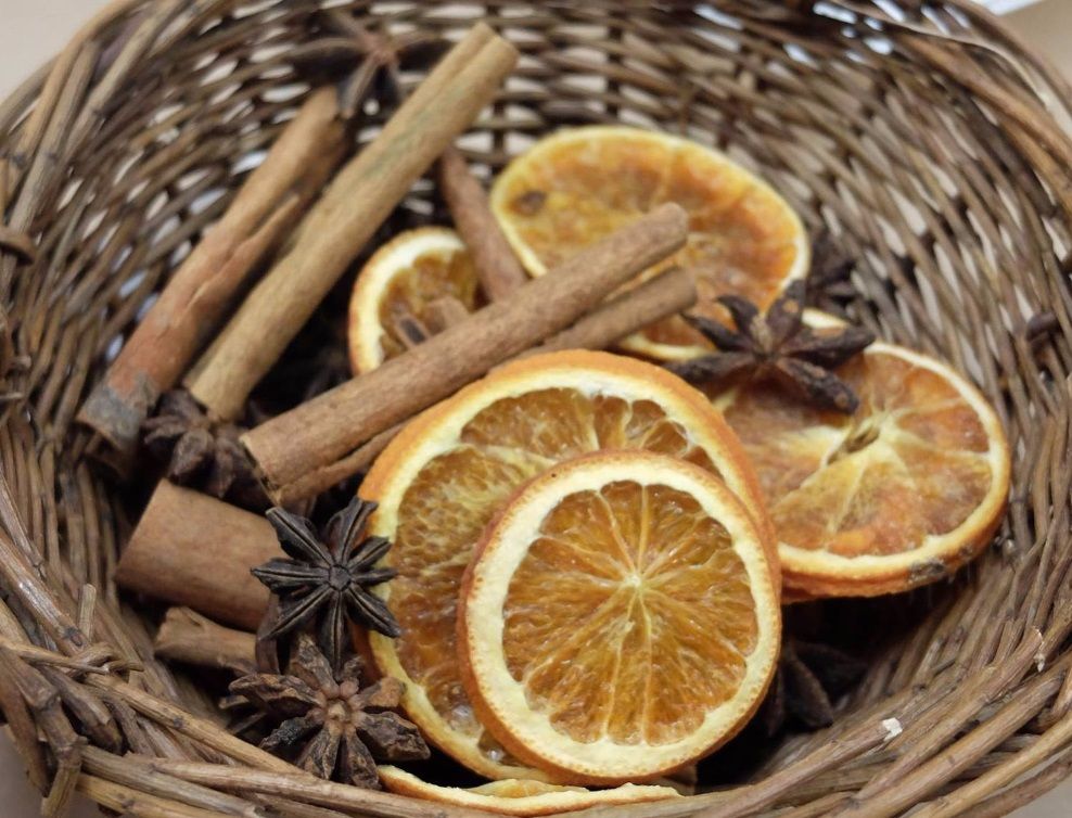 In einem Korb sind Orangenscheiben, Zimtstangen und Sternanis arrangiert, ideal für weihnachtliche Dekoration oder aromatische Zwecke
